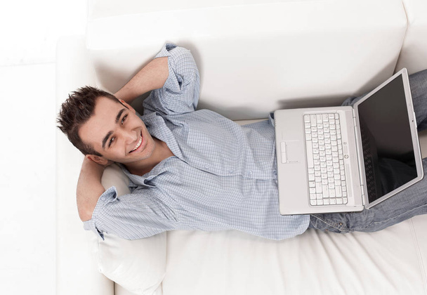 guy working on laptop lying on a sofa - Zdjęcie, obraz