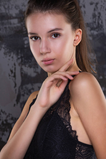Test shoot of elegant brunette model with perfect skin and natural makeup posing against grey wall - Foto, imagen