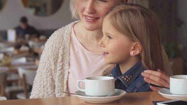 Frau zeigt ihrer Tochter etwas im Café - Foto, Bild