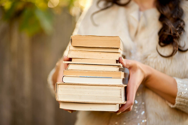 women holding a pile of books with an autumn forest in the background - Photo, Image