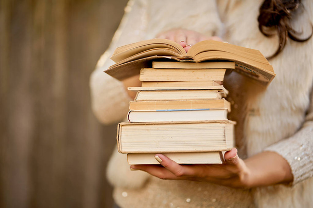 women holding a pile of books with an autumn forest in the background - Photo, Image
