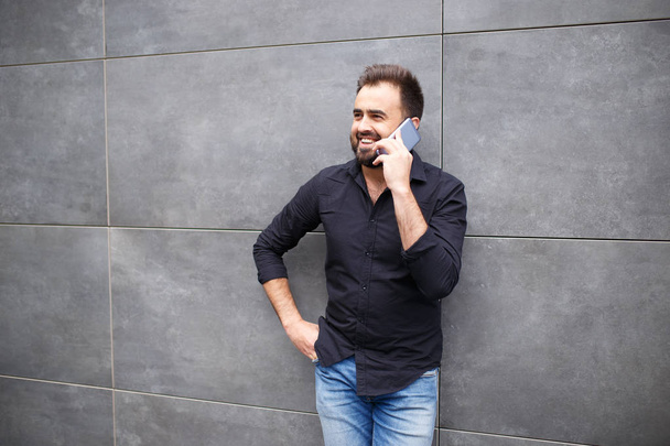 A man with a beard goes and speaks by phone - Zdjęcie, obraz