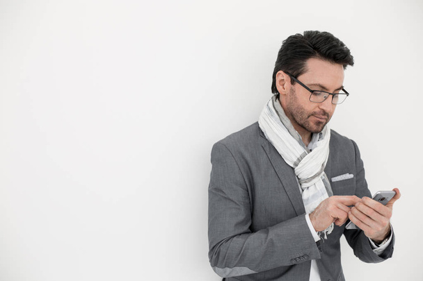 businessman with scarf on neck typing SMS on smartphone. - Foto, imagen