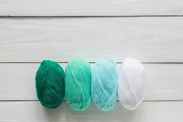 knitting clew in row on white wooden background, pastel green and white colors, top view flat lay with copy space, stock photo image - Photo, Image