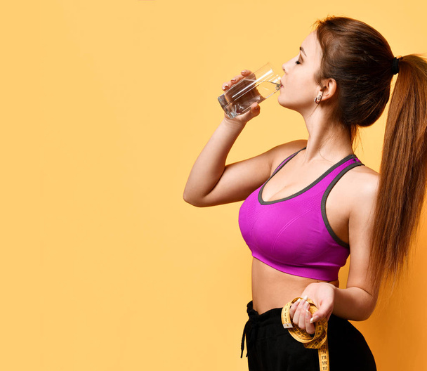 Beautiful sports woman hold tape measure and drink water weight loss life concept - Fotó, kép