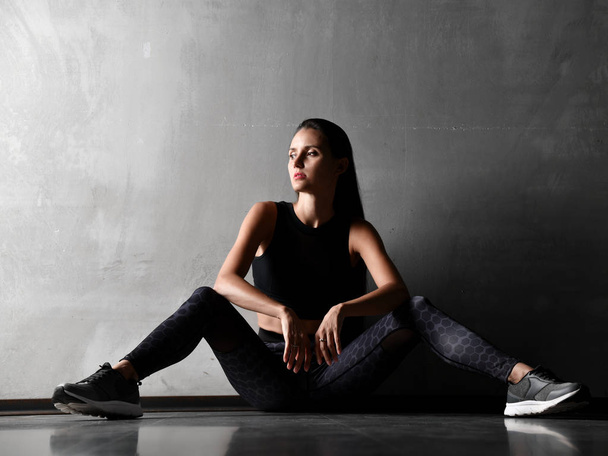 Joven mujer deportiva después de la gimnasia estiramiento ejercicios de fitness entrenamiento sentado en el suelo
  - Foto, Imagen