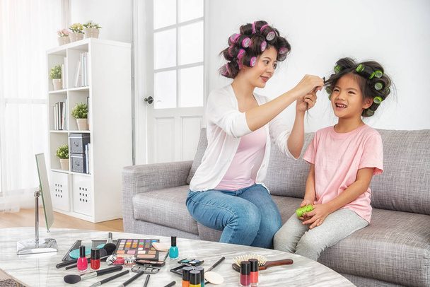 mom helping to set her daughter's hair curly at home - Photo, Image