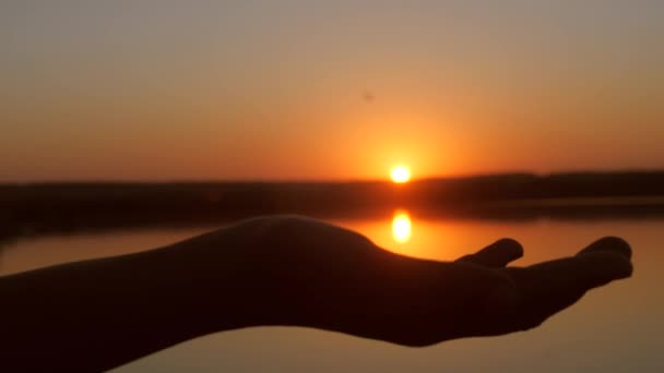 handen met zon in palmen, prachtige zonsondergang over water. - Video