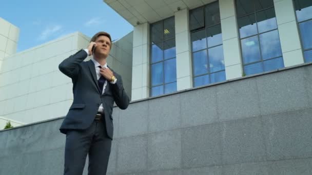 Businessman annoyed after talking with boss on smartphone, deadline pressure - Felvétel, videó