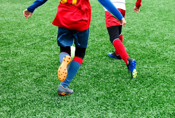 サッカー チーム - 赤、青、白の制服の男の子グリーン フィールド上にサッカーします。ドリブルの男の子。ドリブルのスキル。ゲーム、トレーニング、アクティブなライフ スタイル、趣味、子供の概念のためのスポーツをチームします。 - 写真・画像