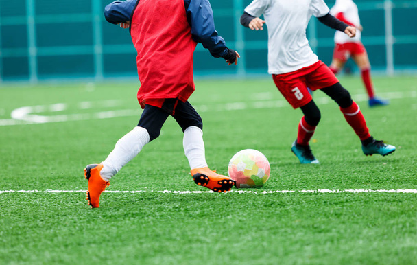 Labdarúgás - fiúk, piros, kék, fehér egyenruhát focizhat a zöld mezőben. fiúk csöpögő. csöpögő képességek. Csapat játék, képzés, aktív életmód, hobby, sport, gyerekek koncepció - Fotó, kép