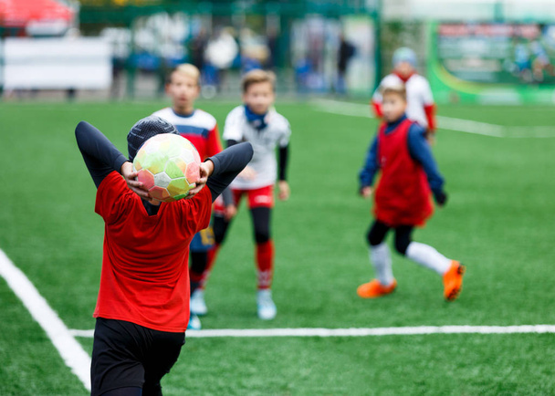 Labdarúgás - fiúk, piros, kék, fehér egyenruhát focizhat a zöld mezőben. fiúk csöpögő. csöpögő képességek. Csapat játék, képzés, aktív életmód, hobby, sport, gyerekek koncepció - Fotó, kép