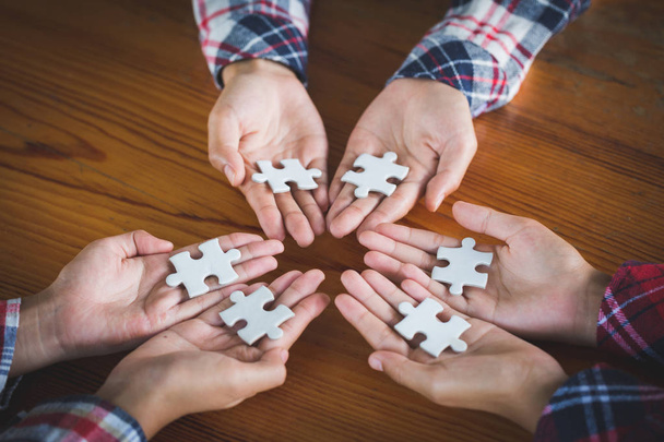 Hands of diverse people assembling jigsaw puzzle, Youth team put pieces together searching for right match, help support in teamwork to find common solution concept, top close up view - Photo, Image