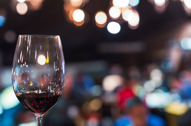 Glass of red wine against blurred bar with lights - Foto, Bild