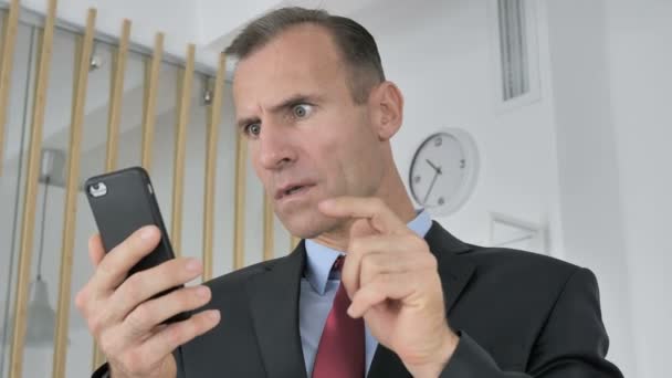 Astonished Middle Aged Businessman Shocked by Result on Smartphone, Wondering - Séquence, vidéo