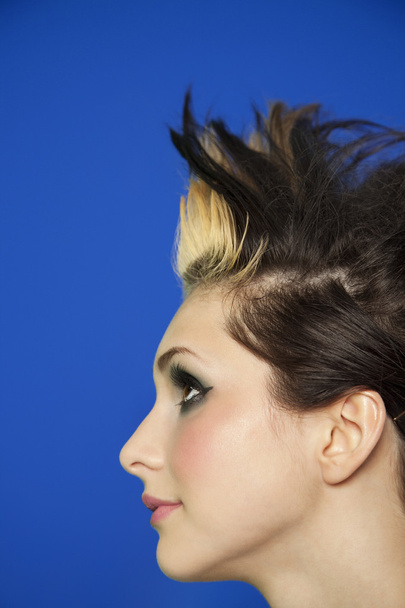 Side view of young woman with spiked hair over colored background - Foto, Imagen