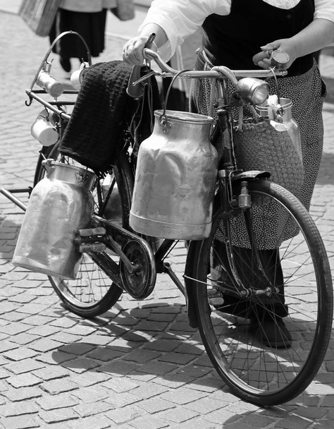 пожилая женщина с молочными банками со старым ржавым велосипедом и черно-белым эффектом
 - Фото, изображение