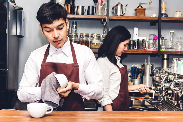 Портрет пары владельцев малого бизнеса, улыбающихся и работающих за стойкой бара в кафе. Пара бариста с помощью кофеварки для приготовления кофе в кафе
 - Фото, изображение