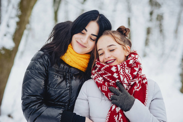 Pretty and young girls wallking in a winter snowy park - Foto, Imagen