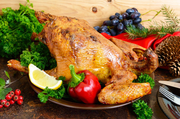 Запечённая курица с зеленью, виноград на деревянном фоне. Праздничная еда. Рождественское меню
 - Фото, изображение