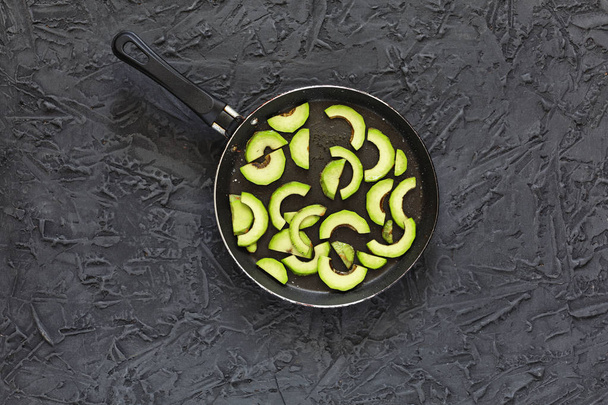 Terveellistä ruokaa. Paistettuja avokadoja oliiviöljyllä grillattuna mustalla pöydällä. Top view, lähikuva, kopioi tilaa
 - Valokuva, kuva