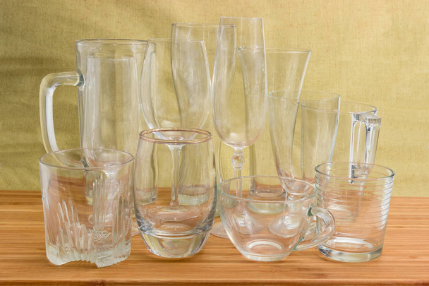 Diferentes copos de cerveja vazios, copos de vinho, copos de vidro e copos em uma superfície de madeira de bambu
 - Foto, Imagem