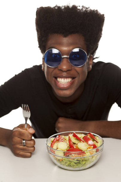 Young handsome Afro american guy eating salad isolated on a white background. healthy food concept - Foto, Bild