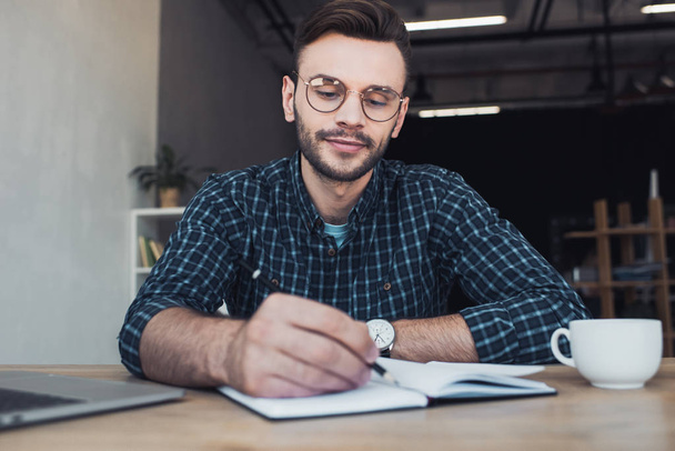portrait of businessman making notes in notebook at workplace in office - Foto, Bild