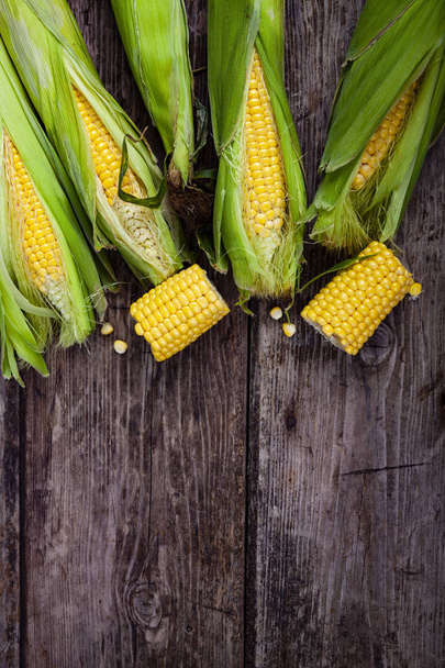 Ripe corn on an old brown wooden table. Yellow  corn, top view - Foto, afbeelding