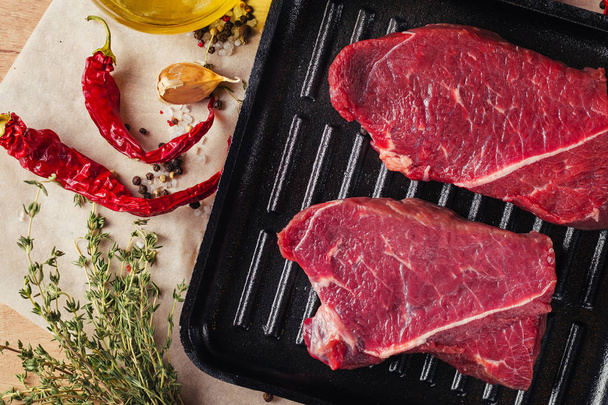 フライパンに、新鮮な生の肉スライスをトップ ビューを閉じます。牛肉ステーキ オリーブ オイルとスパイスで料理の準備ができて - 写真・画像