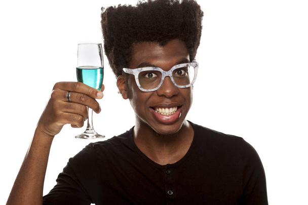 Młody przystojny Afro amerykański facet trzyma kieliszek wina niebieski na białym tle na białym tle. koncepcja życia - Zdjęcie, obraz