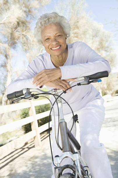 Senior Woman Leans On Handlebars Of Mountain Bike - Valokuva, kuva