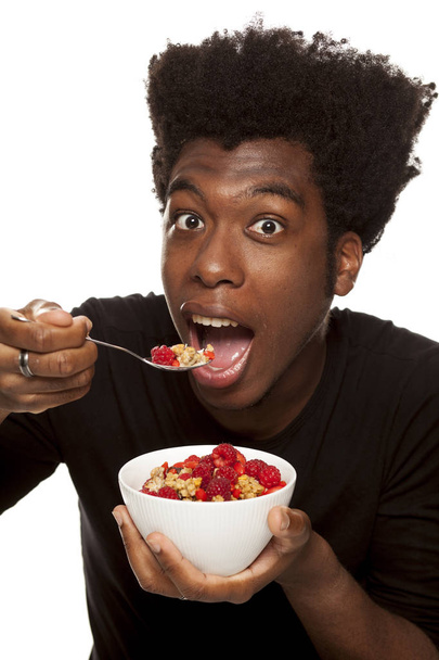 Young handsome Afro american hipster guy eating cereals with fresh fruits isolated on a white background. healthy food concept - Photo, Image