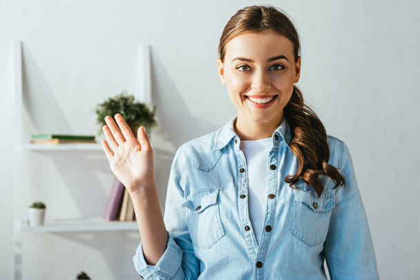 portrait of cheerful young woman waving to camera at home - Foto, Imagem