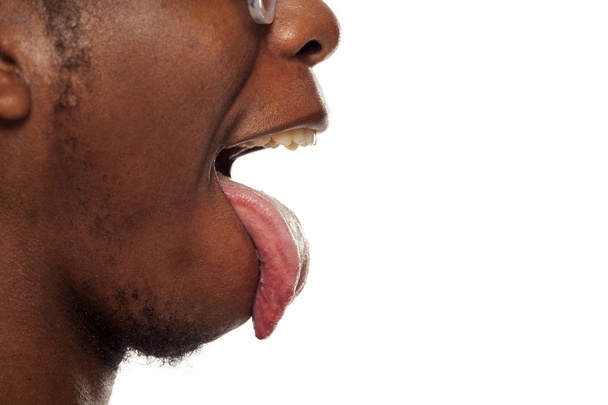Beyaz bir arka plan üzerinde yapışkanlık dışarı dili ile genç bir Afrikalı-Amerikalı siyahi profil görünümü kadar yakın - Fotoğraf, Görsel