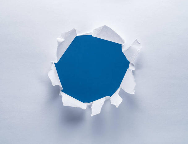 Hole on a paper. Blue background in the hole. - Foto, Imagen