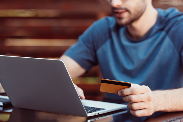 rajattu kuva mies ostoksia verkossa luottokortilla ja kannettava tietokone pöydässä
 - Valokuva, kuva