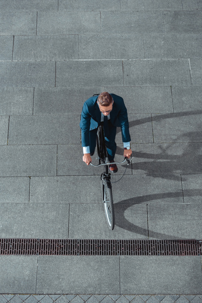 high angle view of businessman in formal wear riding bicycle on street  - Fotoğraf, Görsel