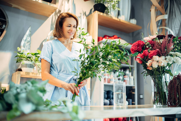 Kadın çiçekçi çiçek dükkanında taze çiçekler tutar. Floristik iş, buketi yapımı  - Fotoğraf, Görsel