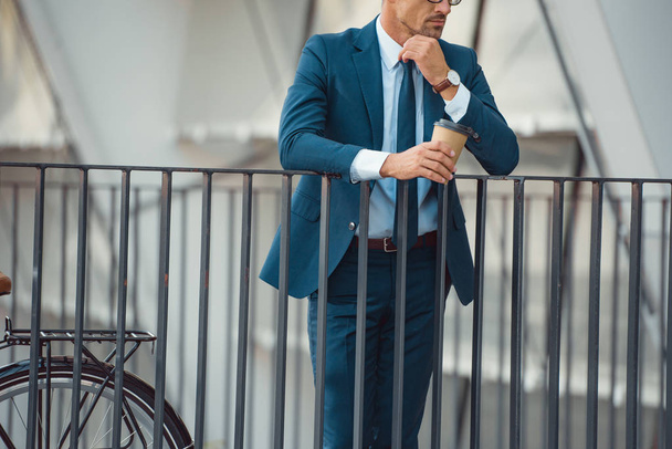 cropped shot of confident businessman holding coffee to go on street - Zdjęcie, obraz