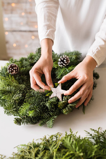 A unrecognizable woman decorating a christmas wreath. - Foto, afbeelding