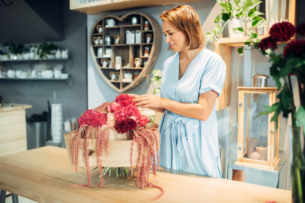 Kwiaciarnia kobieta stawia świeże kwiaty w wazonie w kwiatowy sklep. Florystyka usługi, biznes florystyczny - Zdjęcie, obraz