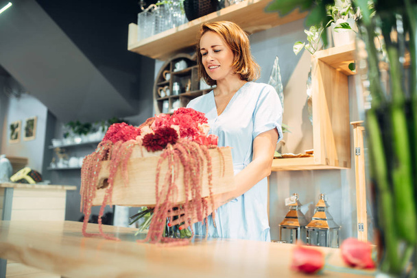 Fiorista femminile mette fiori freschi in un vaso in negozio floreale. Servizio fiorista, commercio floristico
 - Foto, immagini