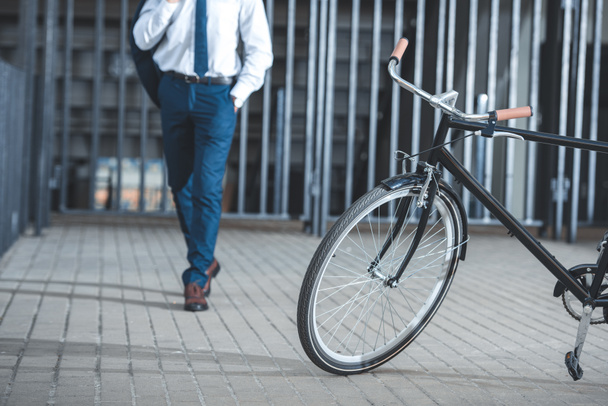 cropped shot of businessman holding suit jacket and going to bicycle parked on street - Fotó, kép