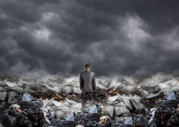 Empresário de pé no meio de um aterro, vista traseira, pilhas de lixo. Empresa ambiental e problema da poluição ecológica
 - Foto, Imagem