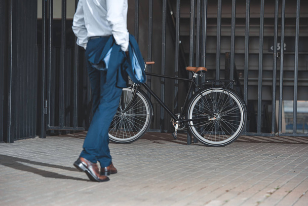 cropped shot of businessman in formal wear going to bike parked on street - Фото, зображення