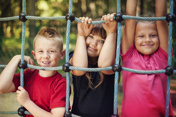 Enfants heureux tenant un filet sur l'aire de jeux
 - Photo, image