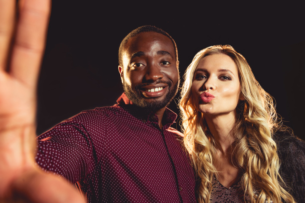 バックライト付きの新年会で selfie を取って陽気異人種間のカップル  - 写真・画像