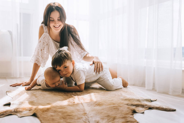 happy young mother spending time with kids while sitting on floor - Photo, Image