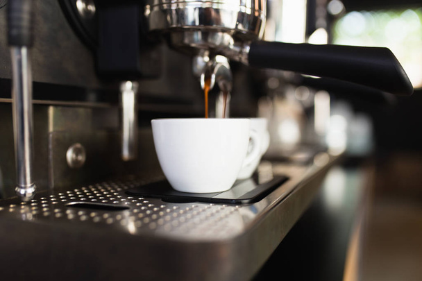 Espresso pouring from coffee machine into coffee cup. - 写真・画像